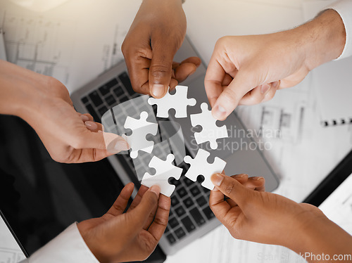 Image of Hands, puzzle and overhead with a business team in the office, working in collaboration on a project. Teamwork, jigsaw piece and laptop with a diverse group of people at work together from above