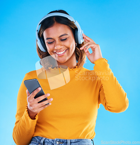 Image of Happy woman, music headphones and phone in studio, blue background and happiness. Female model, smile and mobile for audio, streaming online radio and listening to podcast sound on media subscription