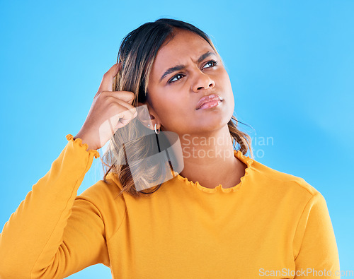 Image of Thinking, confused and pensive woman in a studio with an idea, thoughtful or contemplating face expression. Deciding, doubtful and female model with wonder scratching head gesture by blue background.