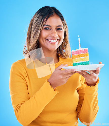 Image of Birthday cake, happy portrait and woman in studio, blue background or party celebration. Female model, rainbow dessert and candle of special event, sweets or smile to celebrate happiness, wish or fun