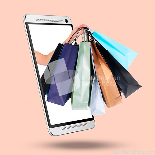 Image of Hands, phone and screen on mockup with shopping bags for purchase, advertising or marketing against a studio background. Hand of shopper with gifts on mobile smartphone display for online ecommerce