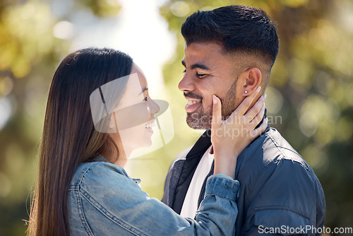 Image of Couple, outdoor and smile for love, care and happiness together in summer. Young woman with hand on face of a man at nature park for affection or trust on happy and romantic date or vacation to relax