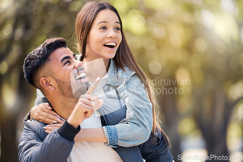Image of Couple, outdoor and pointing at surprise for love, care and happiness together in summer. Young man and woman at nature park for piggyback, laughing or wow at space on happy date or vacation to relax