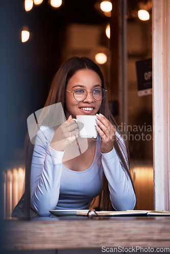 Image of Thinking, dark and happy with a woman in a coffee shop, sitting a table while feeling during the night. Idea, smile and time with an attractive young female drinking a fresh beverage in a cafe