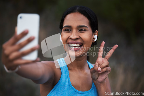 Image of Selfie, peace and fitness with a sports woman outdoor, taking a picture during her cardio or endurance workout. Exercise, running and smile with a happy young female athlete posing for a photograph