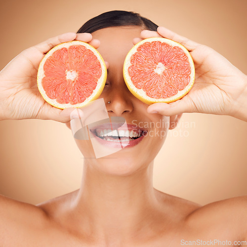 Image of Beauty face, laugh or happy woman with grapefruit for fruit detox, healthcare or natural facial skincare routine. Vitamin c food product, fun studio or playful female nutritionist on brown background