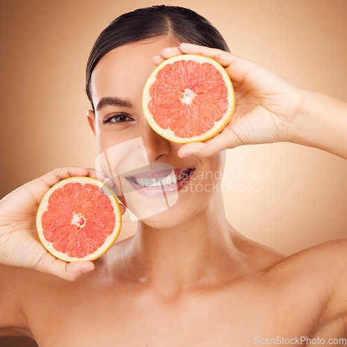Image of Beauty, health portrait and happy woman with grapefruit for fruit detox, healthcare or natural facial skincare routine. Vitamin c food product, studio face and female nutritionist on brown background