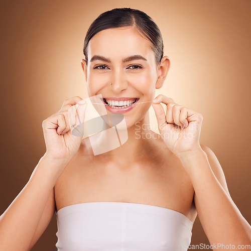 Image of Dental, floss and happy woman cleaning teeth for oral hygiene routine, self care flossing or tooth healthcare. Mouth plaque treatment, face portrait smile and studio female beauty on brown background