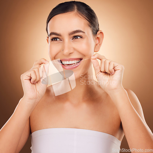 Image of Dental floss, face and happy woman cleaning teeth for oral hygiene routine, self care flossing or tooth healthcare. Mouth plaque treatment, gum care smile and studio female beauty on brown background
