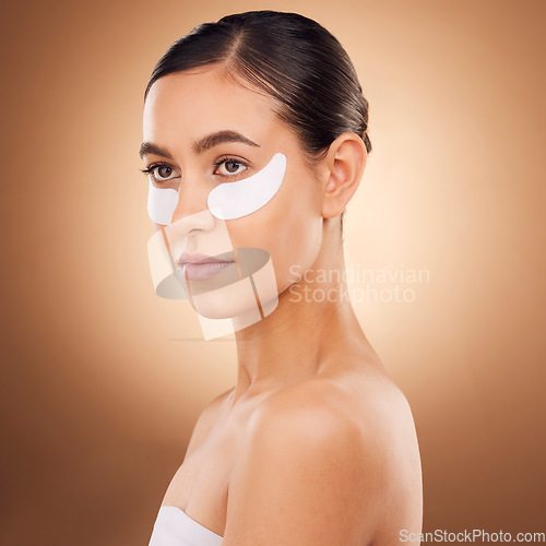 Image of Skincare, face or woman with eye patch for studio dermatology, cosmetic healthcare or beauty treatment. Spa care, facial collagen product or female model with hyaluronic acid mask on brown background