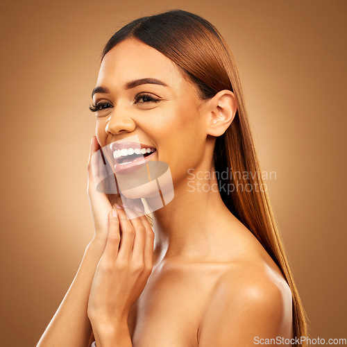 Image of Woman with hand on face, smile and skincare with bronze glow and luxury salon treatment on brown background. Beauty, makeup and skin care cosmetics, hispanic model with straight hair style in studio.