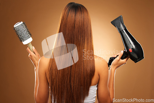 Image of Hair, brush and hairdryer of woman in studio for growth and color shine or healthy texture. Aesthetic female hands with tools for haircare, self care and hairdresser or salon on brown background