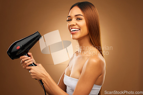 Image of Hair, hairdryer and smile portrait of woman in studio for growth, color or healthy texture. Aesthetic female hands with heat for haircare, self care and hairdresser or beauty salon brown background