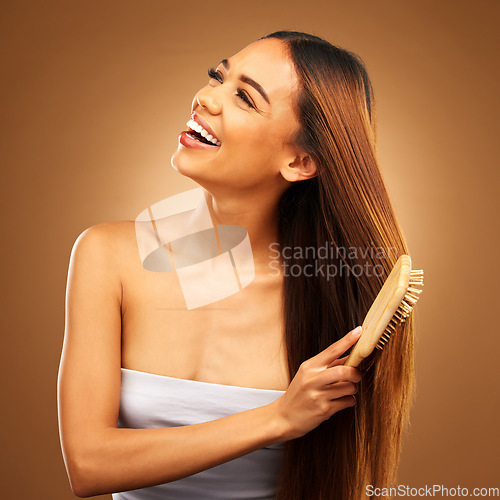 Image of Brushing hair, beauty and a happy woman in studio for growth and color shine or healthy texture. Aesthetic female smile for brush, natural haircare and hairdresser or salon on brown background