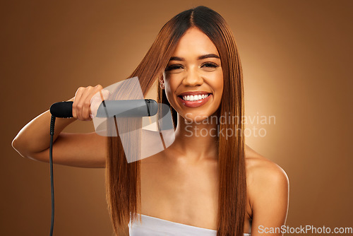 Image of Hair care, portrait of woman with hot iron and smile for luxury salon treatment on brown background. Beauty, haircut and happy hispanic model with straight hairstyle in studio for haircare styling.