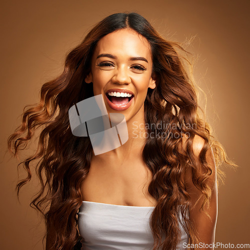 Image of Portrait, hair and laughter with a model woman on a brown background in studio for natural haircare. Face, salon and shampoo with an attractive young female feeling excited by keratin treatment