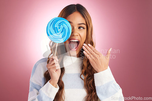 Image of Excited, woman and lollipop candy in a studio with a female feeling happiness from sweets. Smile, surprise and happy model with a sweet dessert treat with isolated pink background and sugar snack