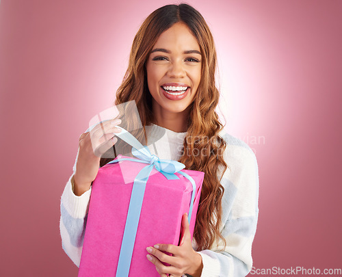 Image of Gift, portrait and happy woman in studio opening present for birthday, celebration or prize on pink background. Smile, box and face of girl with package, giveaway or party gesture while isolated