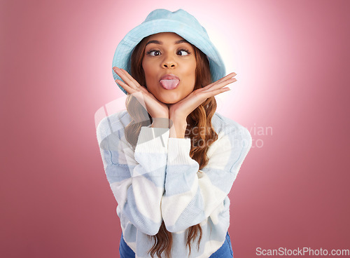 Image of Fashion, comic face and woman with tongue out on studio background for funny face, fun and emoji reaction. Beauty, facial expression and happy girl model for trendy style, cosmetics and casual hat