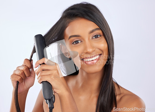 Image of Beauty, health and woman with hair straightener in studio for a straight, long and healthy hairstyle. Happy, smile and portrait of female model with flat iron after hair treatment by gray background.