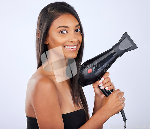 Image of Happy woman, hair care or dryer in studio portrait for healthy natural shine, beauty or wellness on white background. Face of glowing Indian girl model with salon styling equipment tools in grooming