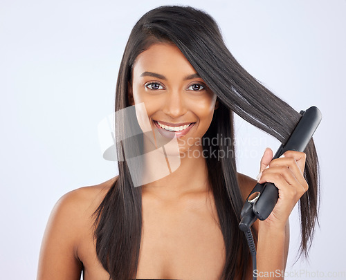 Image of Haircare, cosmetic and female with a hair straightener in studio for a straight, long and healthy hairstyle. Happy, smile and portrait of woman model with flat iron after treatment by gray background
