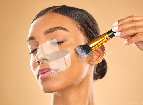 Image of Indian woman, face and makeup, brush and beauty with cosmetic tools and eyes closed on studio background. Skin glow, cosmetology and apply foundation or powder, cosmetics and peace with self care