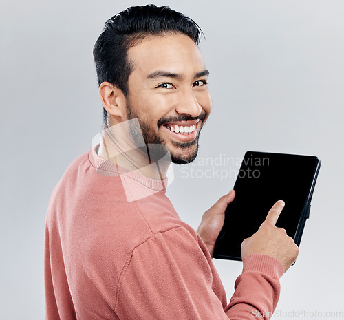 Image of Portrait, smile and Asian man with tablet in studio isolated on a gray background. Face, technology and happy male model with digital touch screen for social media, web scrolling or internet browsing