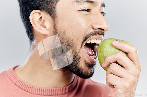 Image of Man is eating apple, health and nutrition with fruit, diet with healthy food and wellness on studio background. Closeup, vegan male and detox with weight loss, healthcare and organic fruits