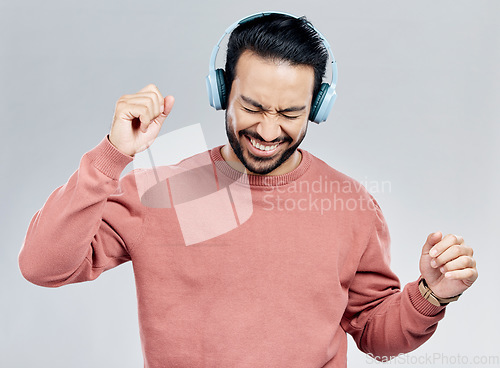 Image of Fun, dance and Asian man with headphones, streaming music and happiness against a grey studio background. Japan, male and guy with headset, listening radio and sounds with movement, silly and smile