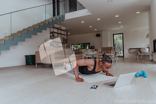 Image of Training At Home. Sporty man doing training while watching online tutorial on laptop, exercising in living room, free space