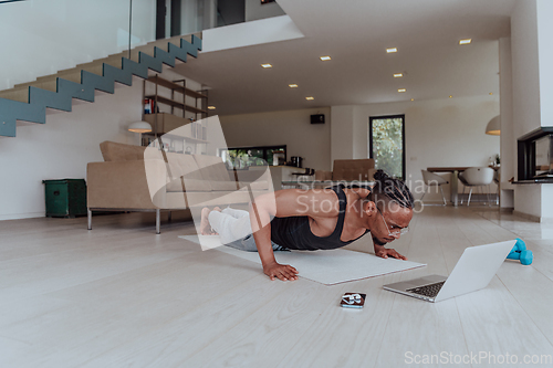 Image of Training At Home. Sporty man doing training while watching online tutorial on laptop, exercising in living room, free space