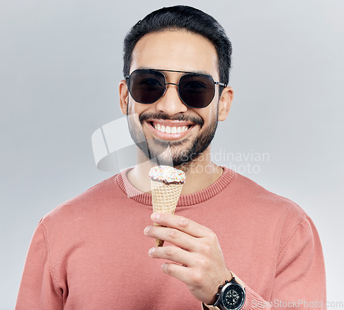 Image of Portrait, sunglasses and ice cream with a man in studio on a gray background enjoying a sweet snack in summer. Food, fashion and dessert with a handsome young male eating or licking an icecream cone