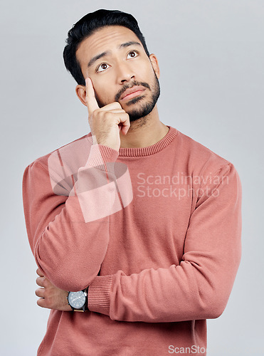 Image of Thinking, confused and question with a man in studio on a gray background looking thoughtful or contemplative. Doubt, idea and memory with a young asian male trying to remember but feeling unsure