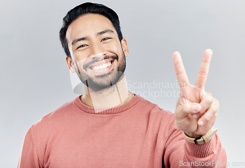 Image of Portrait, smile and Asian man with peace sign in studio isolated on a gray background. Face, v emoji and happy, smiling or excited, young and confident male model with hand gesture or peaceful symbol