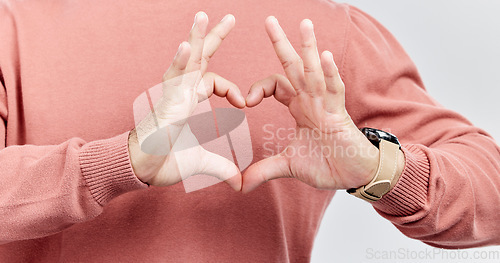 Image of Hands, heart and man with love in studio to show support, thank you or charity sign language. Male model person with hand icon for kindness, care and hope review, motivation or emoji opinion feedback