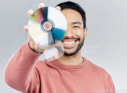 Image of Man, holding and compact disc in studio portrait for smile, happiness and technology by white background. Asian model, student and cd in hand for movie, audio and sound with happy, excited and tech