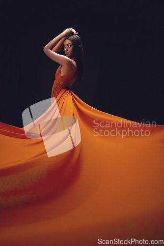 Image of Fashion, woman and elegant with beauty on dark background, portrait and model in orange dress in studio. Indian female, glamour and stylish ballgown with sexy person, luxury style and designer wear