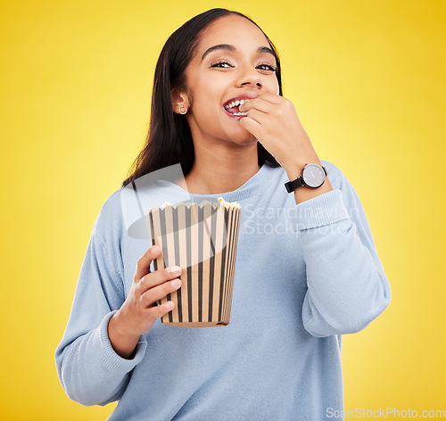 Image of Happy woman is eating popcorn, watching tv and portrait, box with snack for movie on yellow studio background. Streaming service, film and food with corn treat, female with smile and cinema