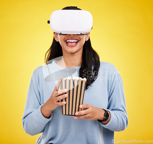 Image of Woman is eating popcorn, happy and VR goggles, snack for watching tv or movie on yellow studio background. Future technology, virtual reality experience and corn treat, cinema and UX with metaverse