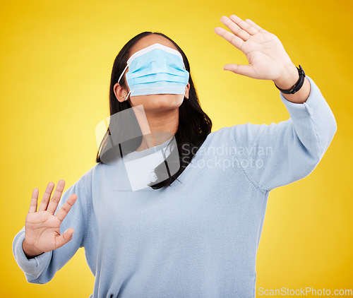 Image of Face mask, covid and woman in blindfold in studio for medical misinformation or conspiracy theory. Deception, virus and female isolated on yellow background for vaccine, protection or pandemic safety