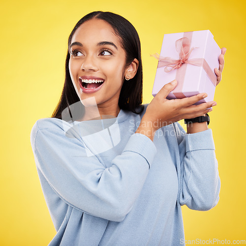 Image of Happy woman, excited and gift box in a studio with a smile from surprise present for birthday. Giveaway prize, isolated and yellow background of a young female student feeling positive and cheerful