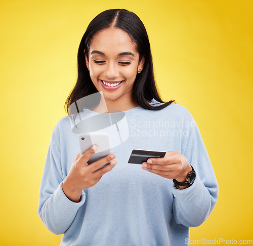 Image of Woman with smartphone, credit card and ecommerce with smile and online shopping on yellow studio background. Fintech, online payment and bank app with happy female, checkout and internet banking