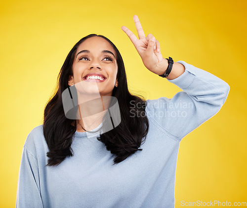 Image of Happy, woman and thinking of peace fingers in studio, background and color backdrop. Female model, v sign and smile with hands for victory, fun mood and happiness of gen z, vote and freedom of emoji