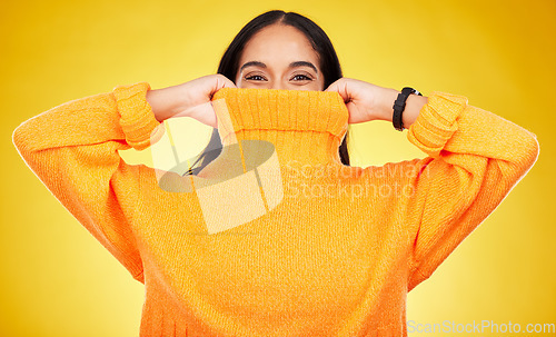 Image of Happy, cover and portrait of a woman with a jersey isolated on a yellow background in a studio. Hiding, winter and a girl holding a jumper up for covering, warmth and bad weather on a backdrop