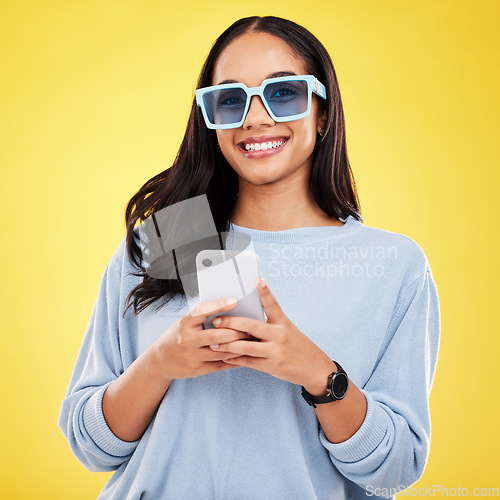 Image of Phone, smile and portrait of woman with sunglasses in yellow studio for social media, website and internet. Communication, mockup space and happy girl on smartphone for chat, message and network