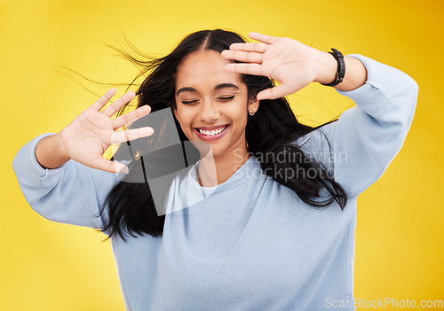 Image of Happy, wind and face of woman with hands on yellow background with smile, happiness and freedom. Hair blowing, mockup space and isolated girl with open palms for beauty, relaxing and calm in studio