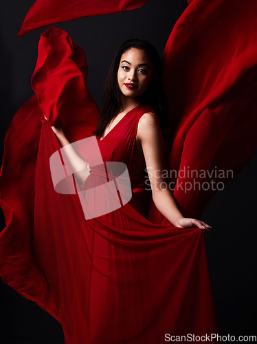 Image of Portrait of woman, art and fashion, fabric on dark background with beauty and aesthetic movement. Flowing silk motion, fantasy and artistic model with smile in red creative designer dress in studio.