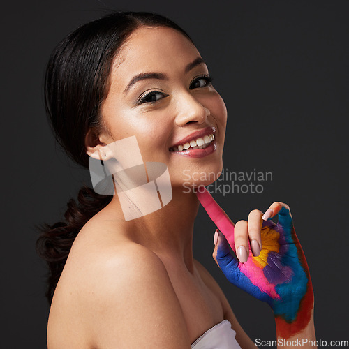 Image of Beauty, woman and face, paint on hand with art, colorful aesthetic and happiness in portrait on studio background. Skin, glow and cosmetics with creativity and female with smile, fashion and creative