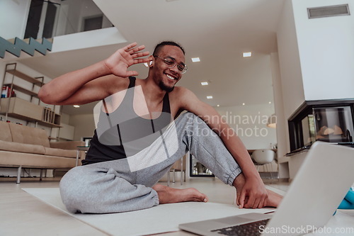 Image of Training At Home. Sporty man doing training while watching online tutorial on laptop, exercising in living room, free space